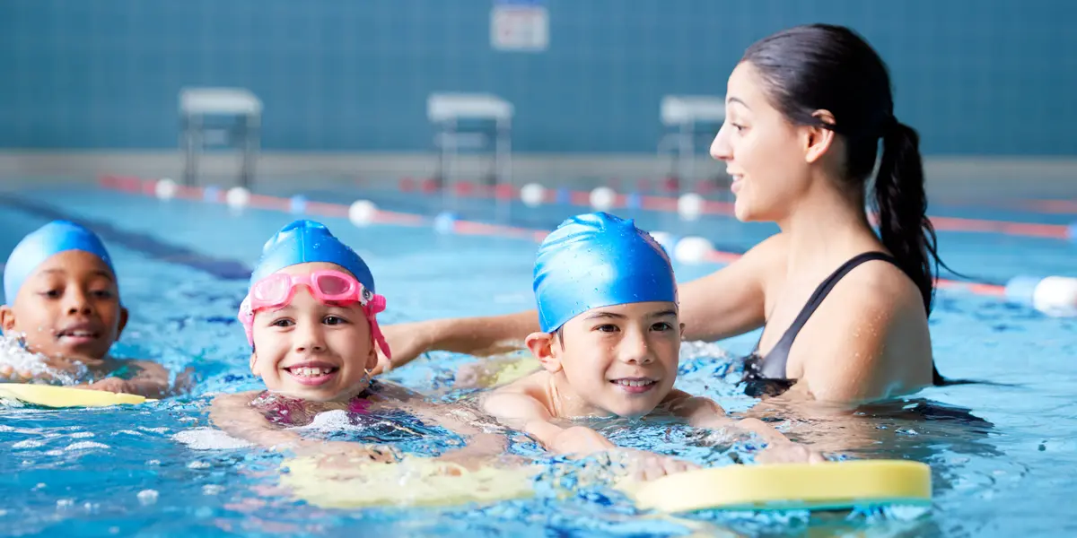 Child learning to swim with an instructor